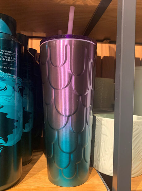 A violet and blue iridescent tumbler sits on a shelf