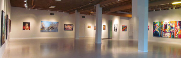 A photograph of the interior of a gallery with an array of artworks hanging on the walls.