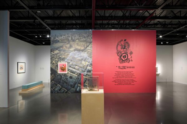Installation view of a wall with a map of mexico city with a text on the right in front of a red wall