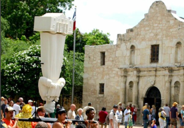 Statue being carried upside down in front of the Alamo