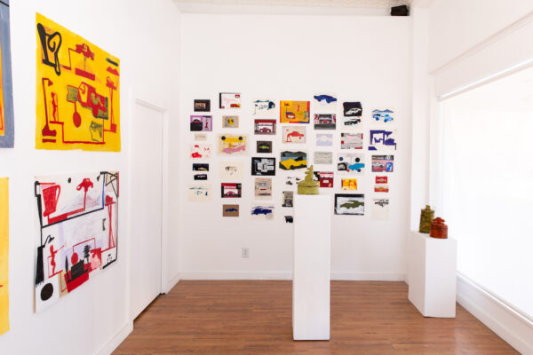 Installation view of works on paper on white walls and ceramics on pedestals