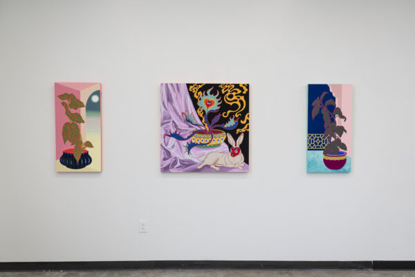 Three paintings hanging on a white wall