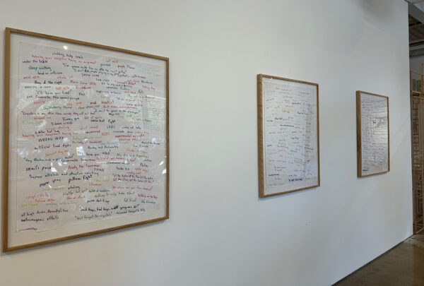 An installation photo of three text-based works hanging on a white wall. Artwork by Austin Lewis.