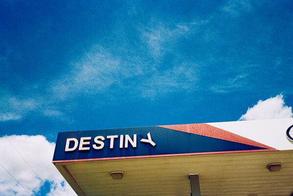 A photograph of a the top of a gas station awning with text that reads "Destiny."