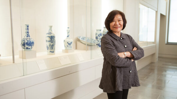 A photograph of curator Emily Sano standing in a gallery with Japanese vases behind her.