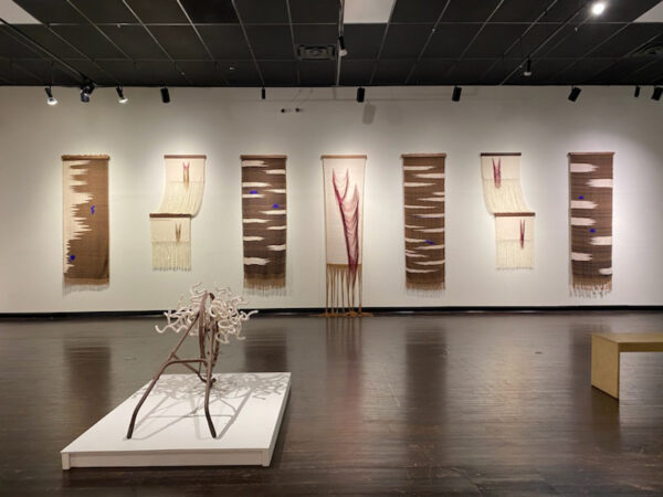 Installation view of long tapestries on a wall made of cotten