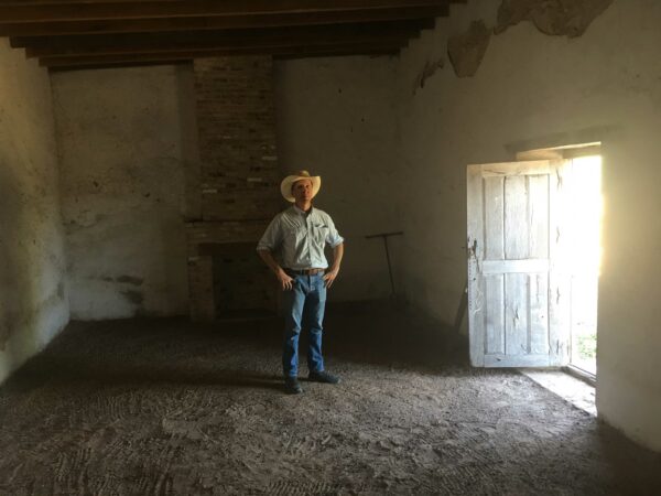 Photo of James McAllen standing in an adobe home