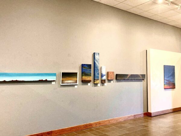 Installation view of landscape paintings on a wall