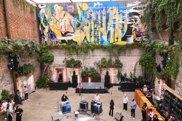 A large, courtyard houses a colorful mural along with musicians playing instruments.