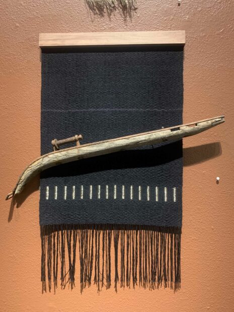Installation image of a tapestry with a scythe