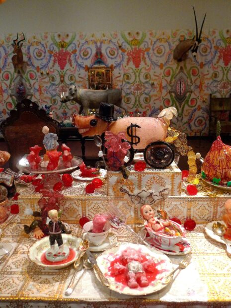 Detail of a place setting on a full table with dishes made from dolls