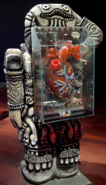 Sculpture of a replica of Cuatlicue deity sculpture with a plastic heart encased in a plexiglass box