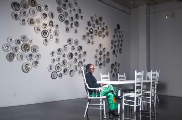 Artist Delita Martin sitting at a table in her installation