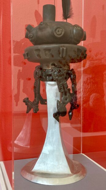 A ceramic sculpture of a Star Wars robot is displayed under glass.