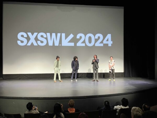 Four men standing on a stage under the SXSW 2024 logo projected on a screen