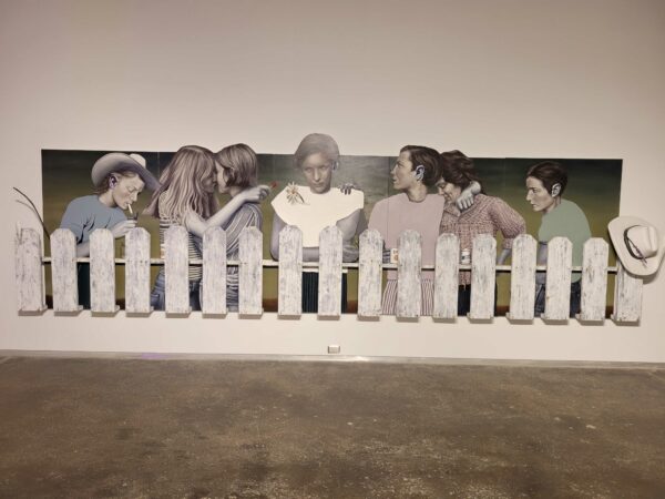 Wall work with multiple people standing behind a white picket fence