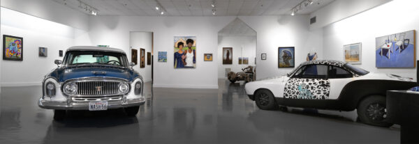 An installation photograph of a gallery featuring two art cars.