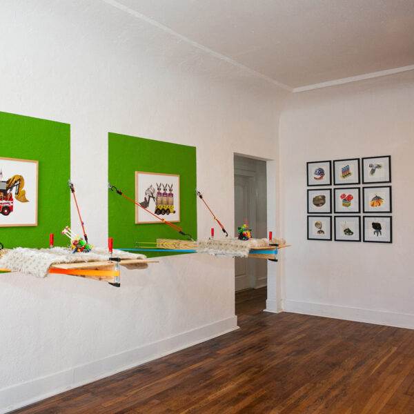 Installation view of a grid of drawings, and two mixed media installations on a wall