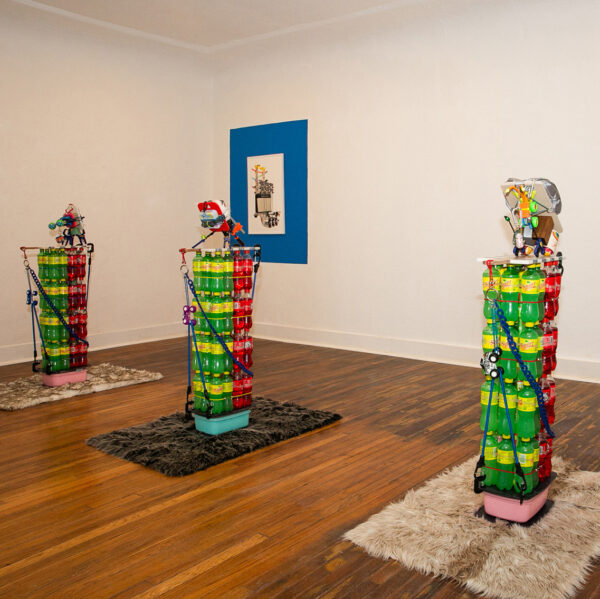 Installation view of stacks of squirt bottles with mixed media sculptures on top