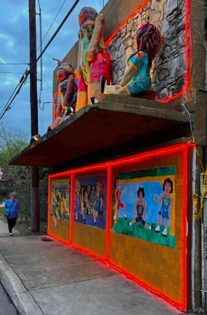 Photo of the facade of a storefront covered ini murals and giant paper mache dolls