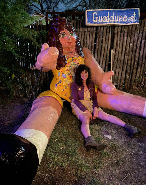 Photo of an artist sitting with a monumental paper mache doll