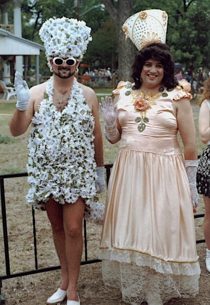 Two people waving at a camera at fiesta San antonio