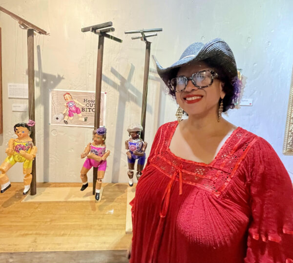 Photo of artist Barbara Felix in front of an installation of marionettes