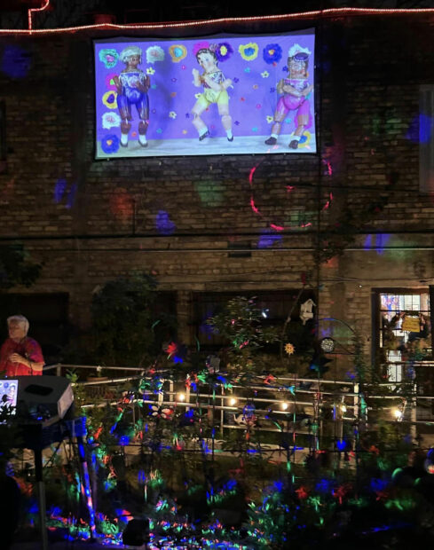 Photo of a video of marionettes dancing against a purple backdrop