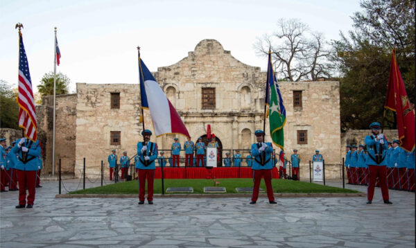 Blue and red uniformed men at an investiture outside of the alamo