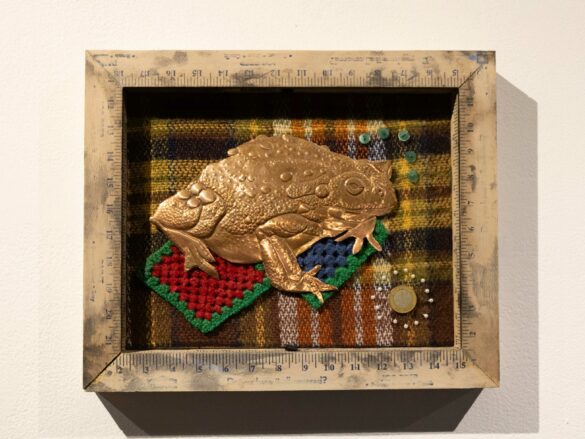 A small aluminum frame toad against an embroidered felt backdrop