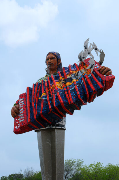 A photograph of a public sculpture by Luis Lopez featuring an accordion player.