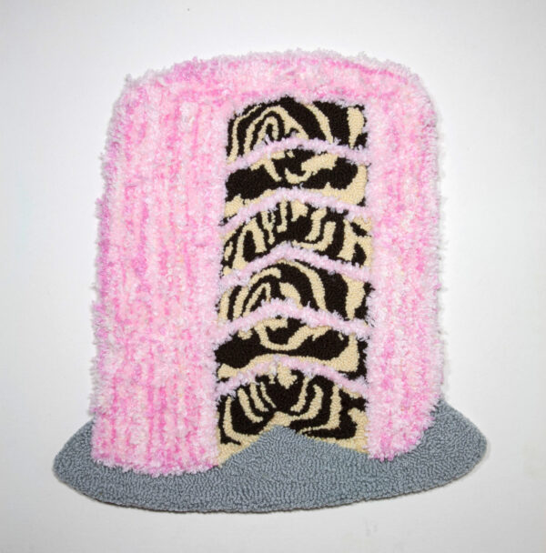 A yarn sculpture depicting a zebra cake covered in pink frosting.
