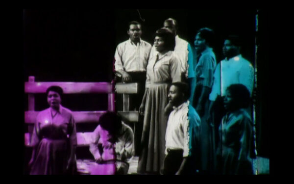 En esta imagen a blanco y negro, cuyos extremos han sido coloreados por un filtro violeta a la izquierda y uno azul a la derecha, un grupo de personas negras con peinados de otra época parece estar cantando.
