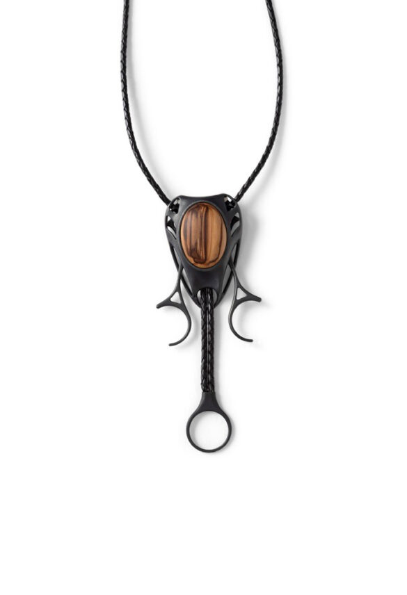 Detail of a black bolo tie with a wood pendant resembling a cicada