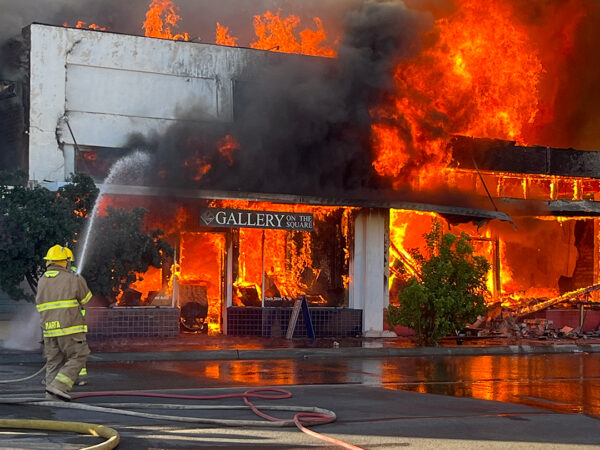 A photograph of a firefighter working to extinguish a fire in a building. 