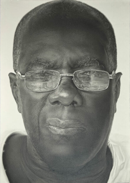 A hyper-realistic graphite drawing of an elderly man wearing glasses.