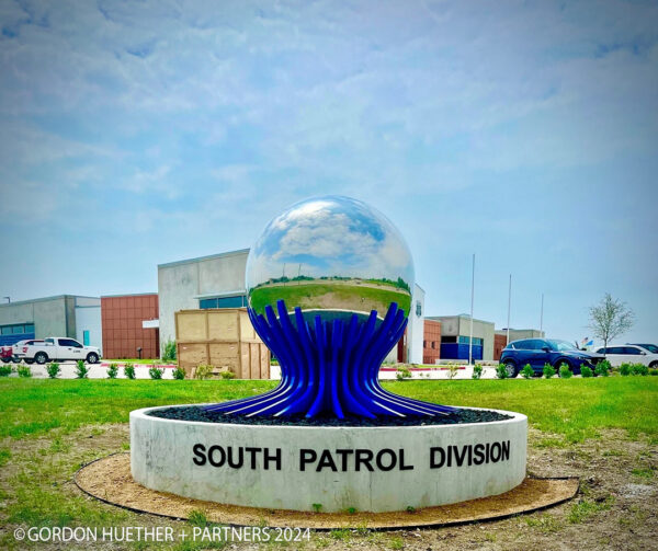 A photograph of a public art sculpture by Gordon Huether featuring a large mirrored sphere.