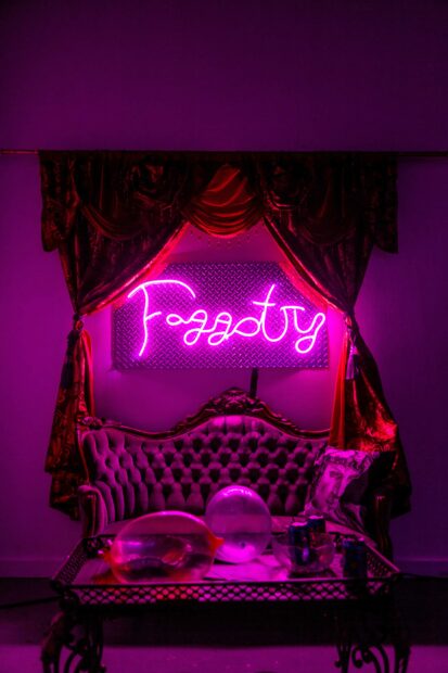 Installation of a neon sign that says "Faggotry" over a victorian couch