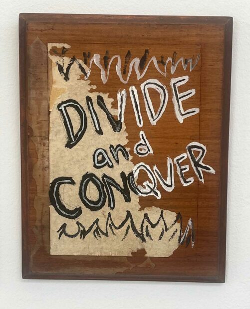 A brown and white painting with the words "divide and Conquer" written across the surface.