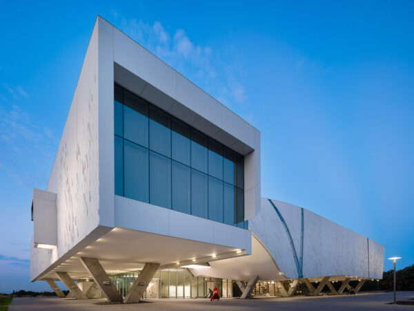 A photograph of a large building with a small sculpture in front of it.