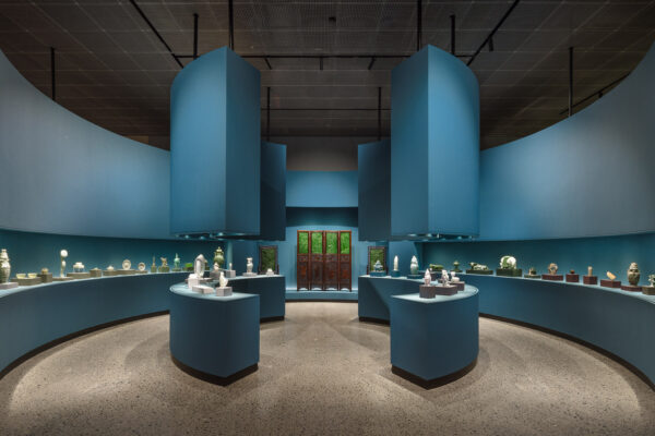 An installation view from an exhibition of Asian art staged in a gallery with blue walls.