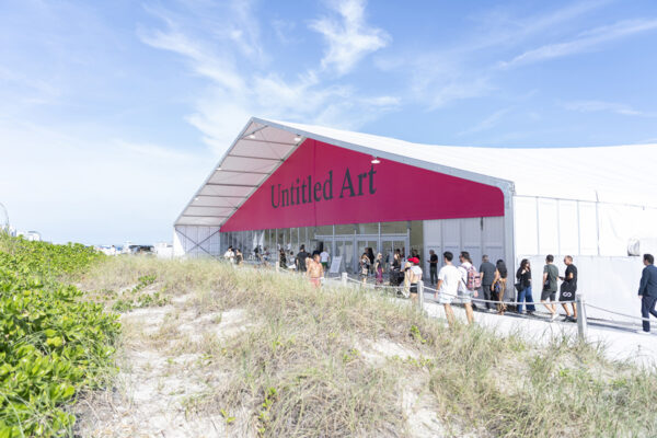 A photograph of a large white tent with a banner that reads Untitled Art.