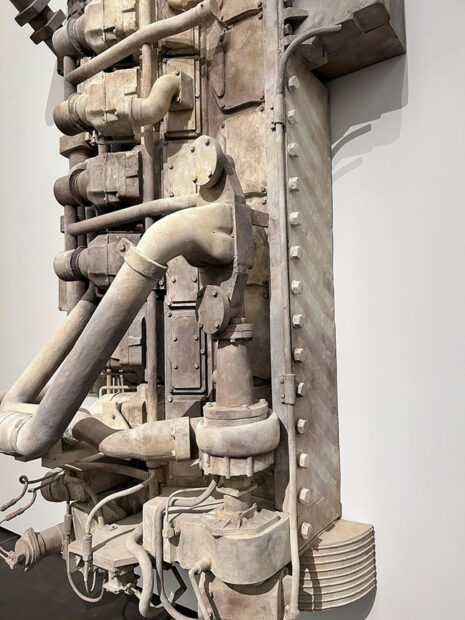 Detail of a cast of a large boat engine hang on a gallery wall.