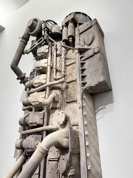 Detail of a cast of a large boat engine hang on a gallery wall.