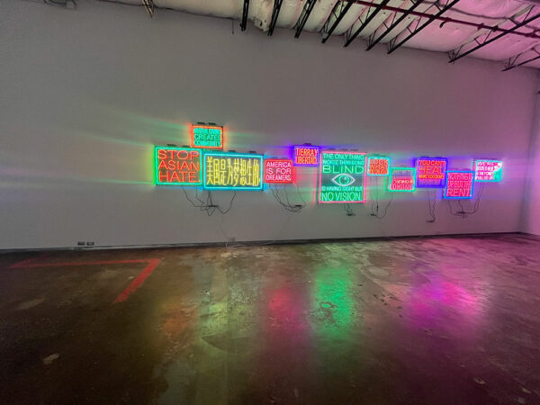 A low-lit gallery with several neon signs on its wall.