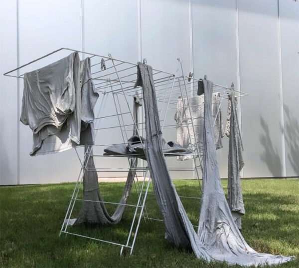 A drying rack holds clothes that have been covered in cement.