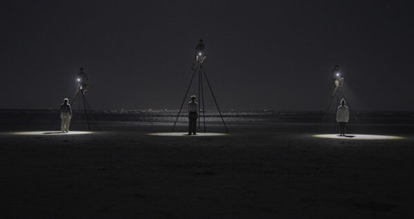 A black and white photograph by Fred Schmidt-Arenales featuring three figures with spotlights.