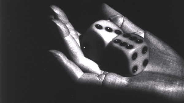 A black and white image of a womans hand holding two oversized dice.