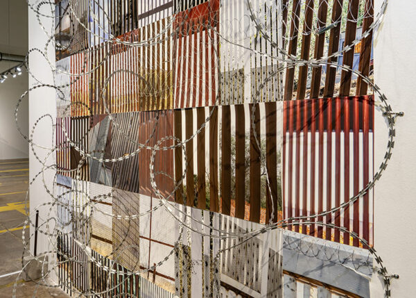 A collection of photographs of different sections of the border wall installed with razor wire in a gallery.