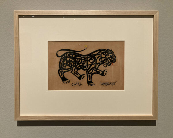 A framed and matted calligraphic arabic work of typography that forms the shape of a lion raising its front paw